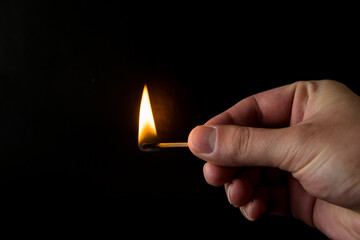 burning match with flame in hand on isolated on black background