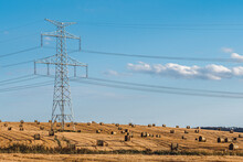 Straw Bales On The Field Near High Electricity Pylons
