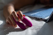 A woman lies in bed holding a clitoral vibrator and watching porn on a laptop. The girl has sex online