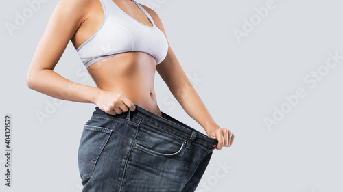 Woman showing result after weight loss wearing on old jeans