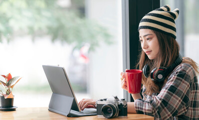 young hipster female student working on laptop computer while sitting at the table in co-workspace.