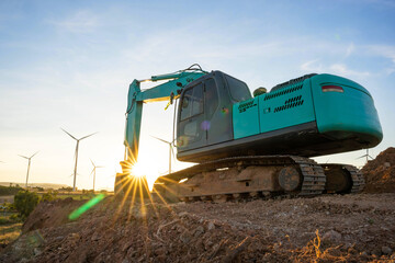 Backhoe and wind turbines that are generating electricity in the background, the concept of sustainable resources, Beautiful sky with wind generators turbines, Renewable energy