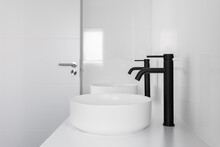 White Tiled Bathroom With Two Wash Basins And Black Faucets.