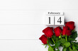 Wooden calendar 14th February and roses on white background