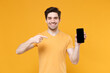 © ViDi Studio - Young smiling man 20s in casual print design t-shirt hold point index finger on mobile cell phone with blank screen workspace copy space mock up isolated on yellow background studio portrait.