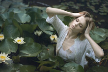 Blond Woman In A Pond Among White Water Lilies