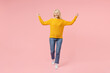Full length of happy elderly gray-haired blonde woman lady 40s 50s years old in yellow basic sweater standing doing winner gesture clenching fists isolated on pastel pink background studio portrait.