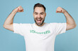 © ViDi Studio - Strong funny young bearded man 20s wearing white volunteer t-shirt showing biceps muscles isolated on blue color background studio portrait. Voluntary free work assistance help charity grace concept.