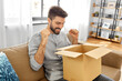 © Syda Productions - mail delivery, shipment and people concept - happy smiling man with open parcel box at home