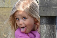 Close-up Portrait Of Cute Girl Sticking Out Tongue