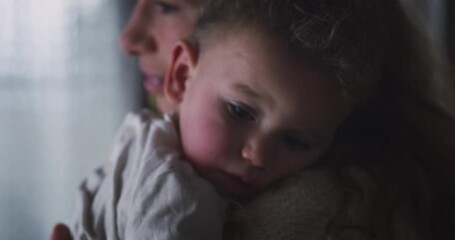 Wall Mural - Cinematic close up shot of young peaceful mother cuddling on her arms and singing lullaby to her sick with fever toddler baby boy with red cheeks at home. Concept of health care,child care, illness,mo