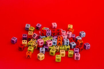 Colorful wooden cube beads with letters on red festive background, word 