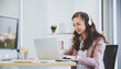© Danai - Concentrated Caucasian female in headphone  working in modern office
