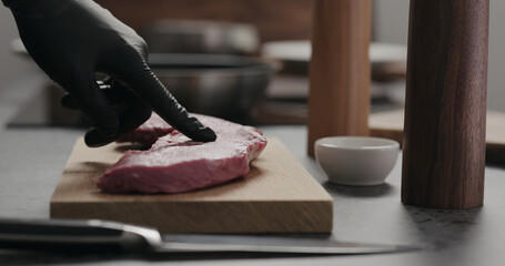 man cut raw beef steak on oak board