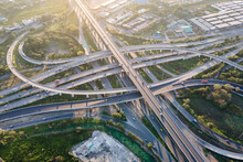 Aerial View Of Road Interchange Or Highway Intersection With Busy Urban Traffic Speeding On The Road. Junction Network Of Transportation Taken By Drone.