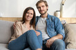 © opolja - Happy young Caucasian couple relax on cozy sofa at home hugging look in distance dreaming together