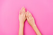 top view of female hands with pastel enamel on fingernails on pink background