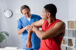 © LIGHTFIELD STUDIOS - mature chiropractor working with african american man in sportswear on blurred foreground
