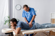 © LIGHTFIELD STUDIOS - middle aged chiropractor working with injured back of african american patient on massage table in clinic