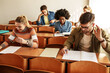 Group of college  students taking a test in a classroom.Educational concept.	
