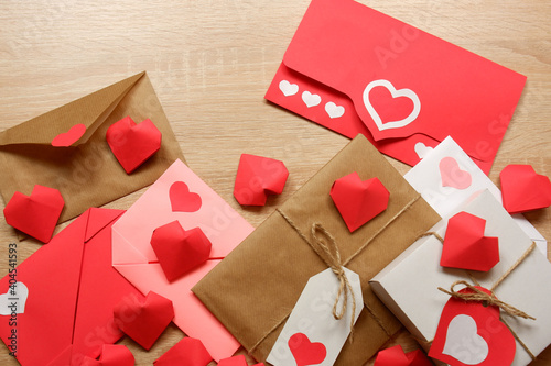 Envelopes from red paper, craft paper with hearts, red, pink, white paper envelopes, white gift box with red label in a heart form, gift wrapped in brown craft paper, tied with twine with a bow 