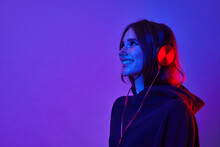 Fashion Hipster Woman Smiles And Wear Headphones Listening To Music Over Color Neon Background At Studio.
