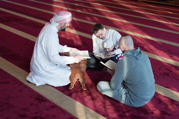 Wall Mural - Group of Muslim people in mosque reading Koran