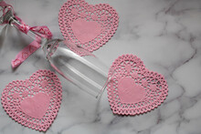 Champagne Glass Surrounded By Three Pink Hearts On A White And Gray Marble Background.