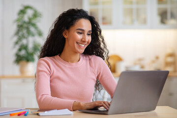Poster - Happy beautiful young female freelancer working on laptop in kitchen