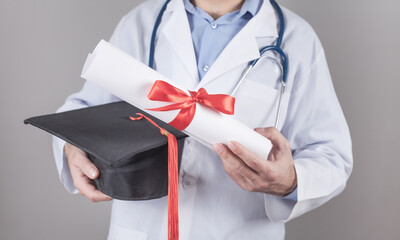 Wall Mural - Caucasian doctor holding graduation hat and diploma. Medical education