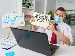 Wall Mural - Man in face mask shows Business continuity plan while online meeting.