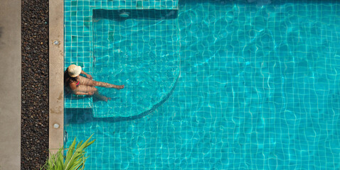 Wall Mural - People swimming in pool. In summer sunny day swimming pool blue color clear water and people enjoying and top view angle. People relaxing in summer hot day in hotel pool and bird eye view angle