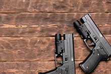 Two Toy Guns With Laser Sights On The Brown Wooden Table Background With Copy Space.