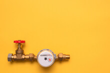 Water Meter And Red Valve On The Pipe Part On The Yellow Flat Lay Background With Copy Space.