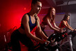© alfa27 - fit women at the gym riding on spinning bike in red neon lighted smoky space. healthy lifestyle and sport concepts