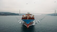 Ship-following Flock Of Seagulls Flies In Front Of The Bow Of Container Ship Underway In Bosphorus Sea. Aerial View As A Cargo Ship Ploughs Through Waters. Close Up Of Bulbous Bow Breaking Waves
