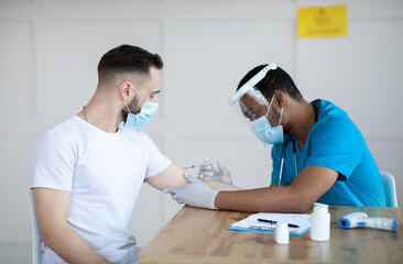 Poster - Young guy receiving injection of covid-19 vaccine at clinic. Black doctor immunizing male patient against coronavirus