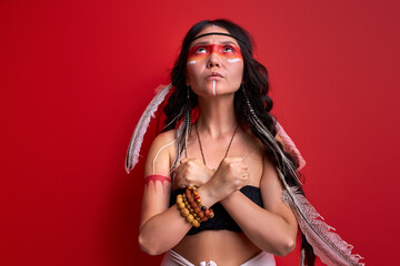 young pagan female is a shaman isolated in studio on red background, people are different from others. Individuality