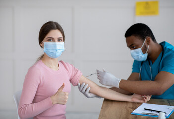 Poster - Young woman getting covid-19 vaccine injection, showing thumb up gesture, recommending coromavirus immunization