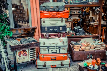 Racked suitcases in front of antique shop. colorful old suitcases. old plaques and books