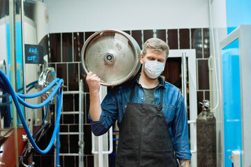 Sticker - Worker of beer production plant in protective mask carrying cistern on shoulder