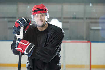 Aufkleber - Mature male hockey player in sports uniform, helmet and gloves holding stick