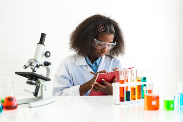 African american cute little girl student child learning research and doing a chemical experiment while making analyzing and mixing liquid in glass at science class on the table.Education and science 