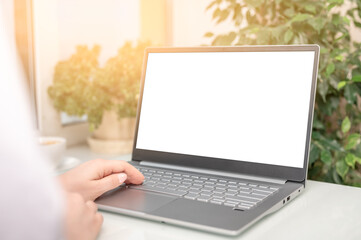 Poster - hand typing laptop computer showing blank white screen on table office place. blank screen laptop computer template. Notebook screen for application user interface presentation mockup