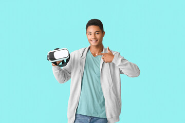 Wall Mural - Teenage African-American boy with virtual reality glasses on color background