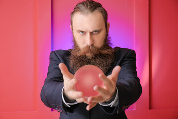 Wall Mural - Male fortune teller with crystal ball on color background