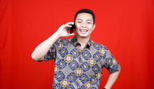 Asian Man Calling Happy Expression With Batik Clothes Isolated Red Background