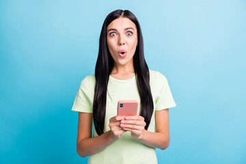 Photo portrait of astonished woman holding phone in two hands isolated on pastel blue colored background