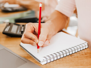 Man writes business information in notebook at workplace in office with calculator and laptop