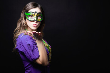 Mardi gras party, masquerade. Woman with a carnival mask and beads on the black background with copy space